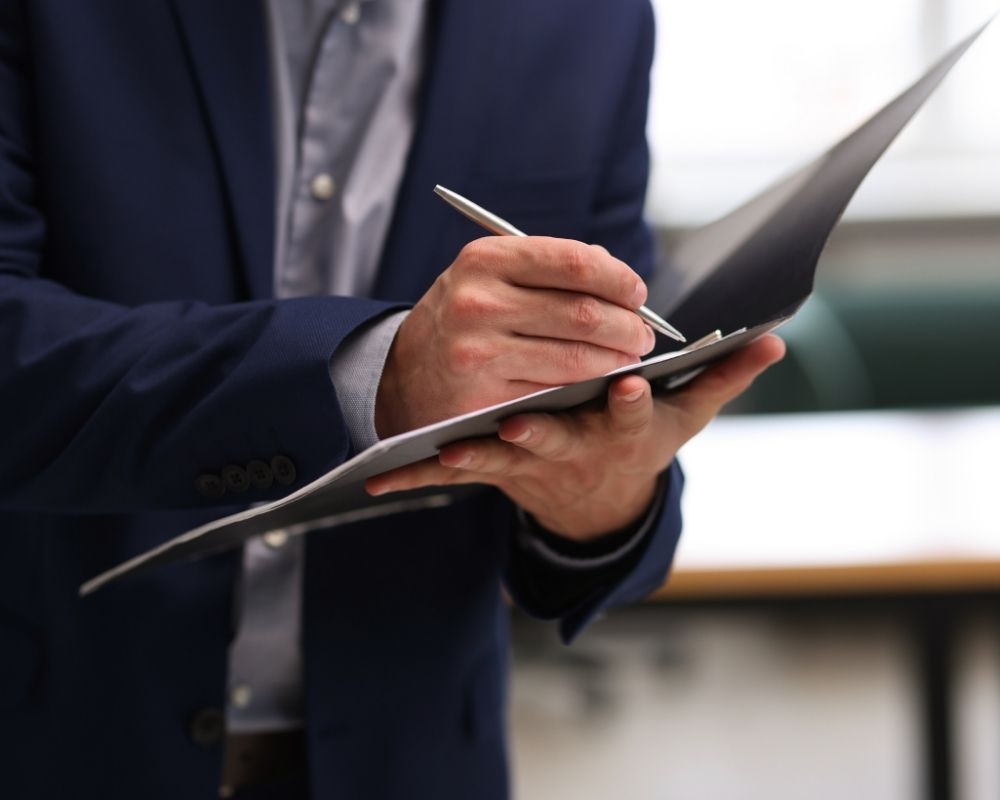 man writing notes on paper
